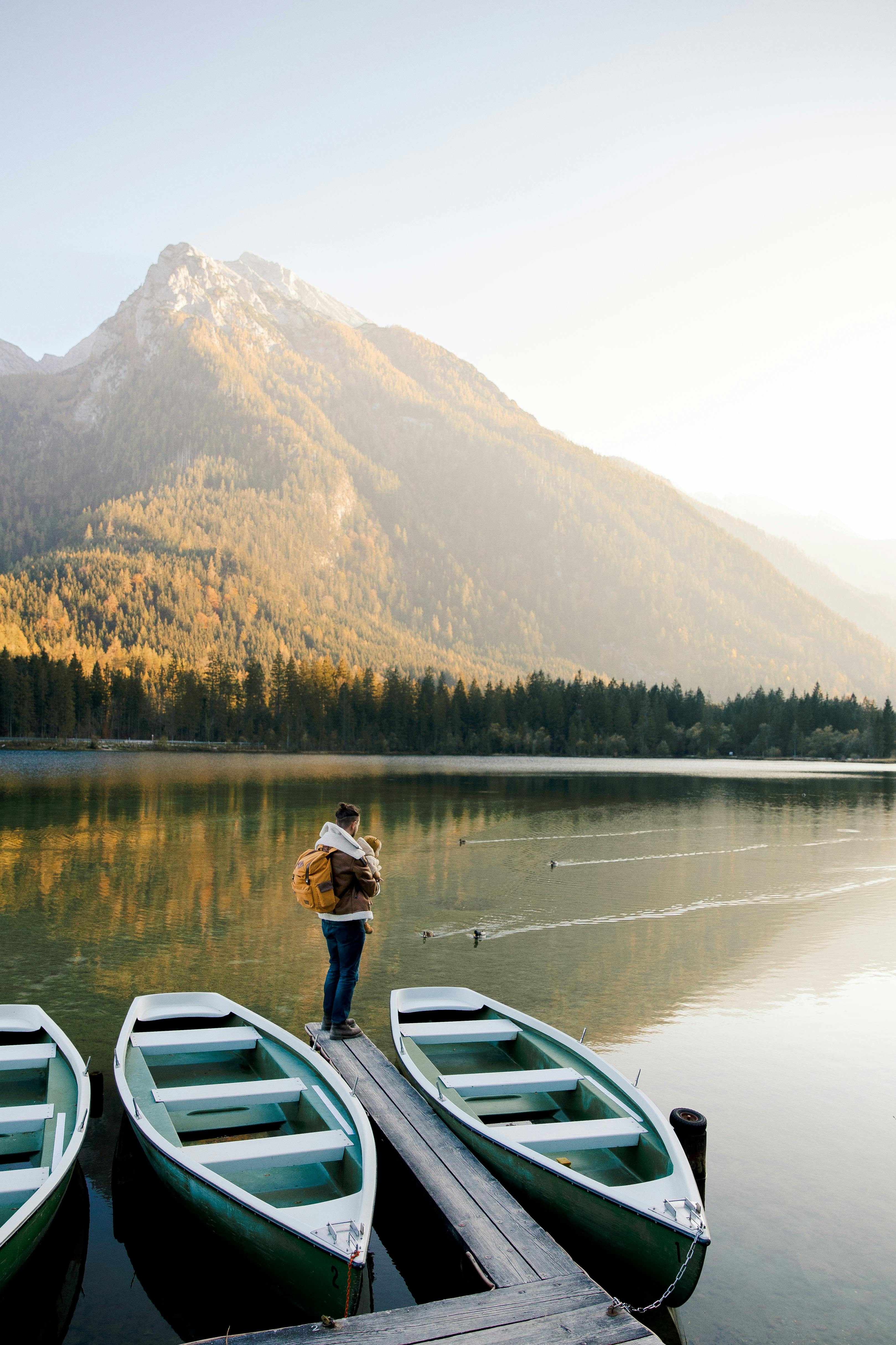 photo of man standing beside lake