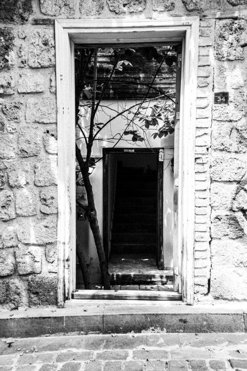 Free Rustic stone doorway leading to hidden staircase in black and white photo. Stock Photo
