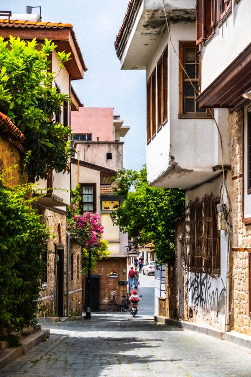 Free A vibrant narrow street in an old town with lush foliage and historic architecture. Stock Photo