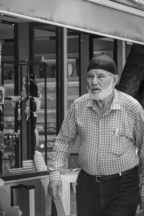 Free Black and white photo of an elderly man in a market setting, conveying culture and tradition. Stock Photo