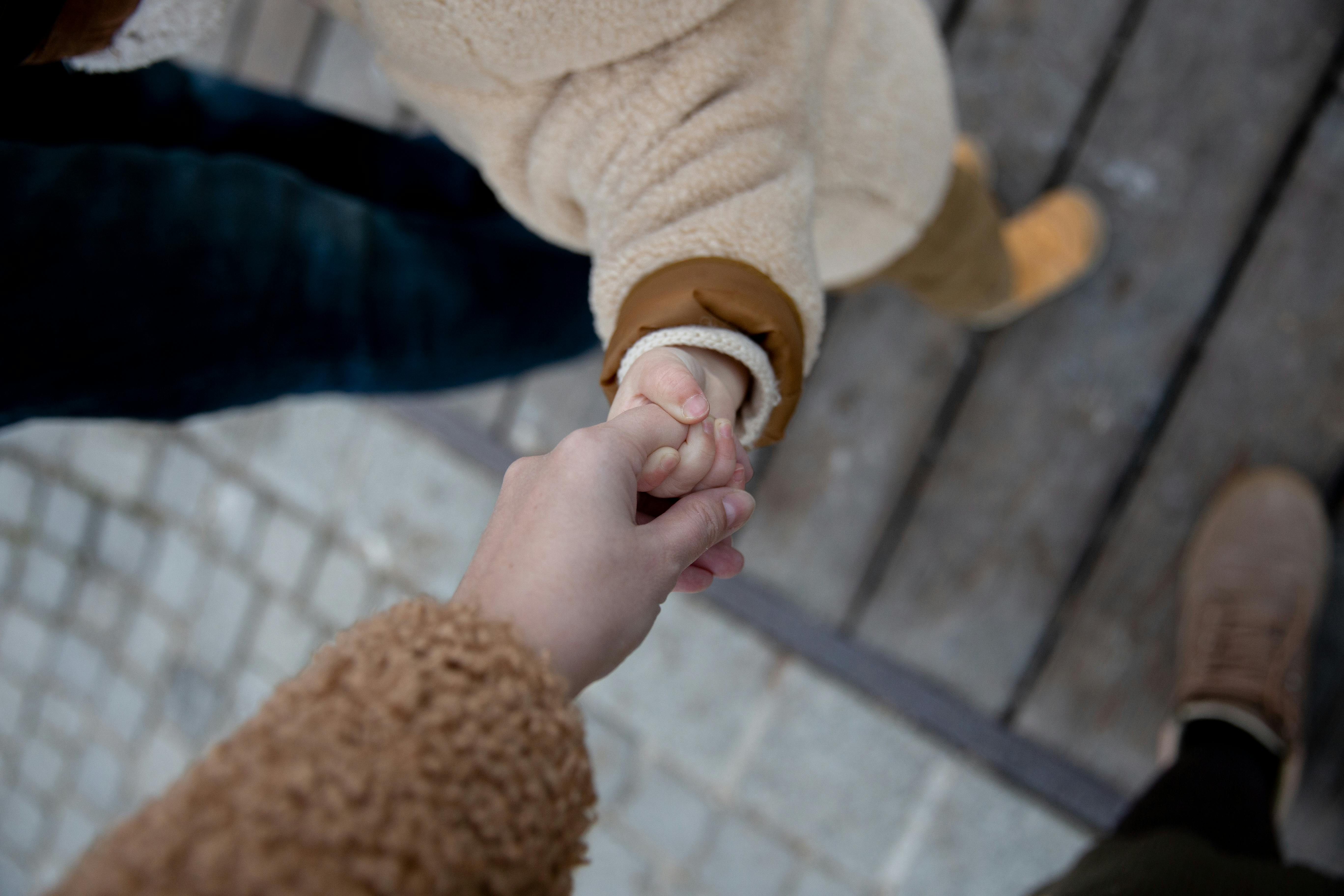 photo of person holding baby s hand