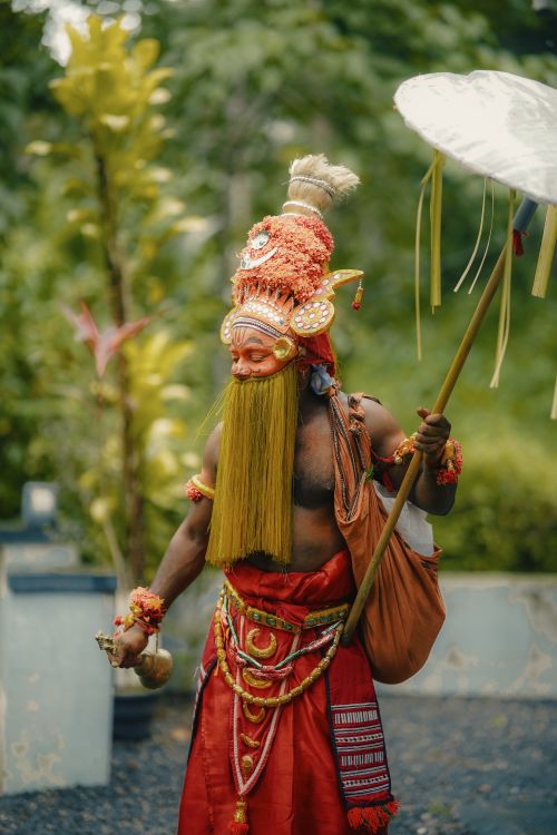 Free Colorful Theyyam performer holding a parasol in Kerala, India. Stock Photo