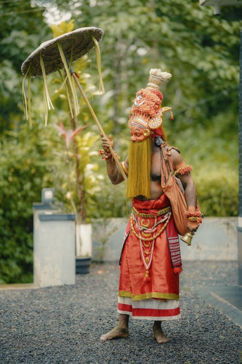 Free Colorful traditional Theyyam performer holding a ceremonial umbrella in Kozhikode, Kerala, India. Stock Photo