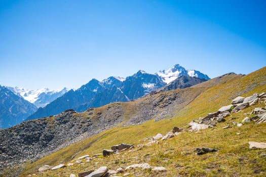 A stunning view of the snow-capped Tian Shan Mountains under a clear blue sky in Almaty, Kazakhstan.
