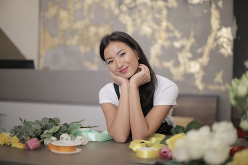 Free Woman in White T-shirt in Front of Flowers on the Table Stock Photo