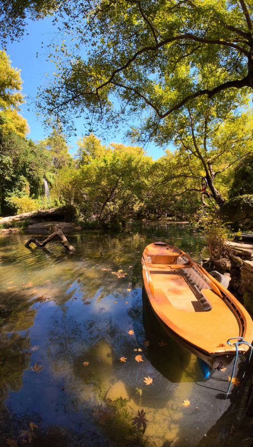 Free A tranquil boat on a reflective lake surrounded by autumn trees in Antalya, Türkiye. Stock Photo
