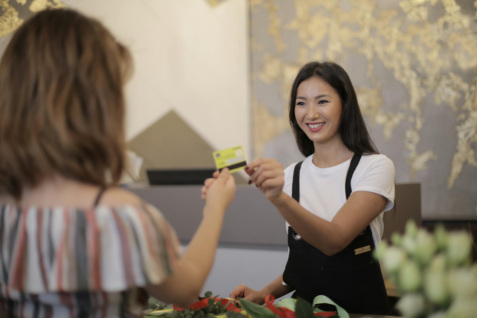 Florist smiling while accepting payment in a flower shop.