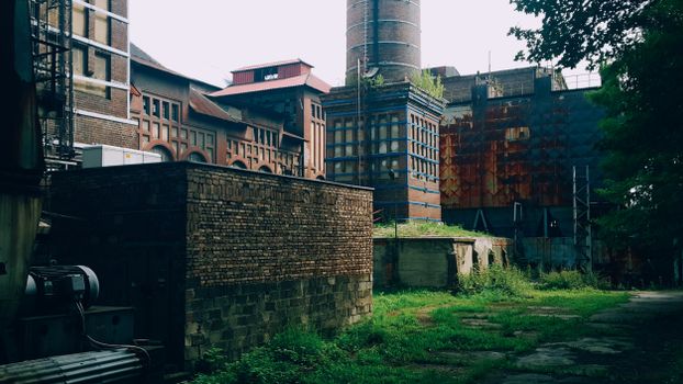 A rustic, abandoned industrial facility with overgrown vegetation.