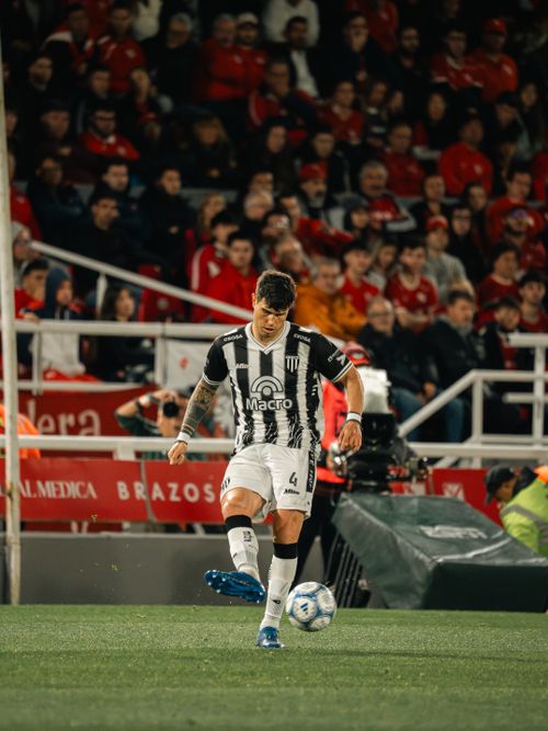 Free Soccer player wearing black and white uniform kicking a ball on a crowded stadium field. Stock Photo