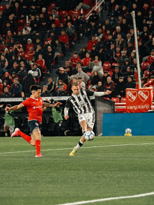Free Players compete in a lively soccer match amid cheering crowds. Stock Photo