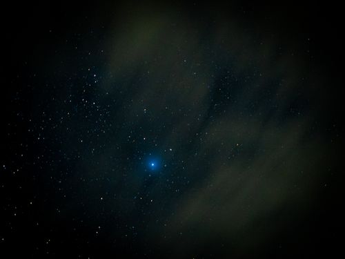 Free A serene night sky filled with stars and a prominent blue star shining through wispy clouds. Stock Photo