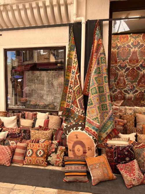 Free Vibrant assortment of traditional Turkish kilim rugs and cushions on display outdoors. Stock Photo