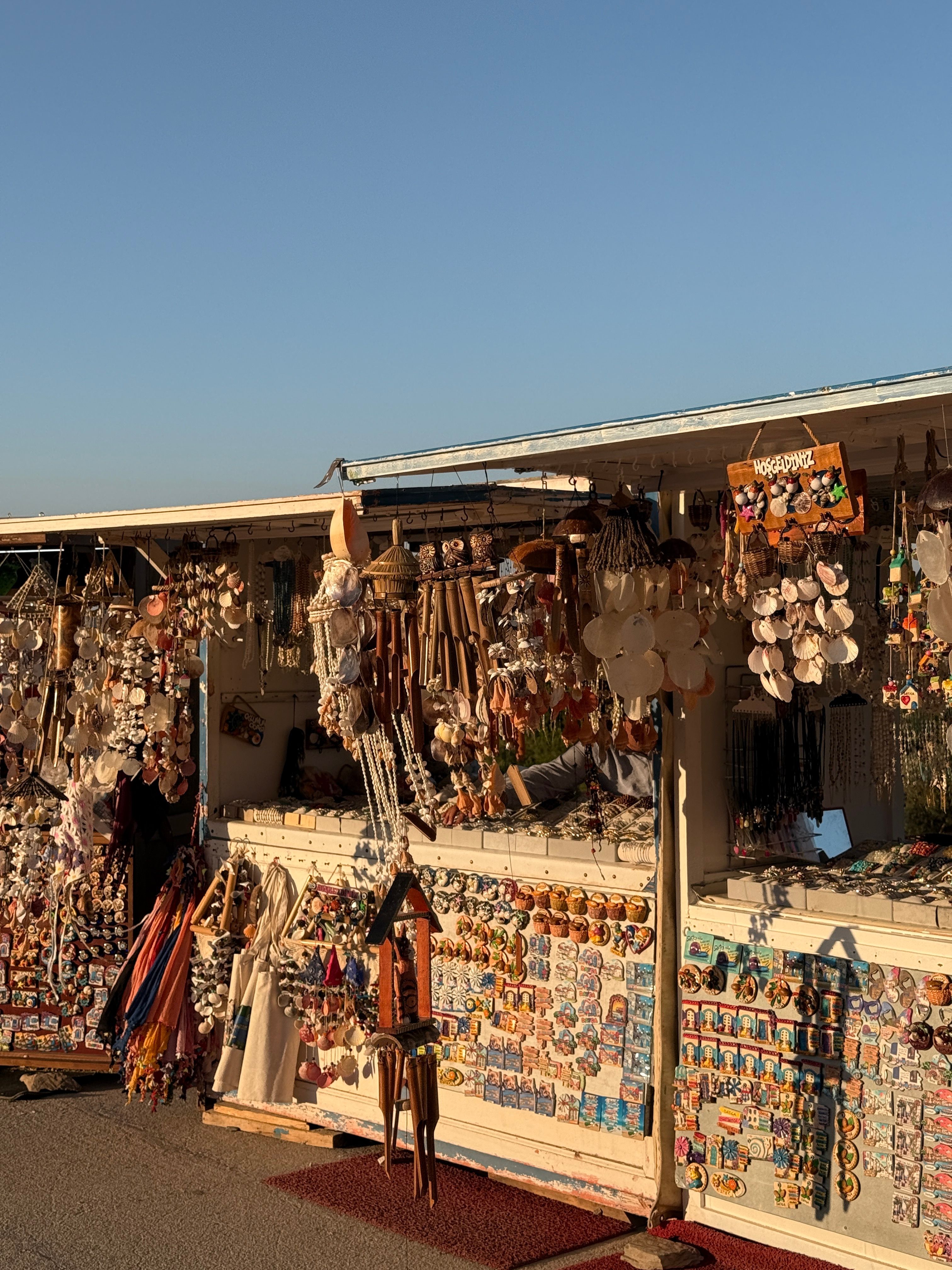 Lively outdoor souvenir market stalls display a variety of decorative goods under the summer sun.