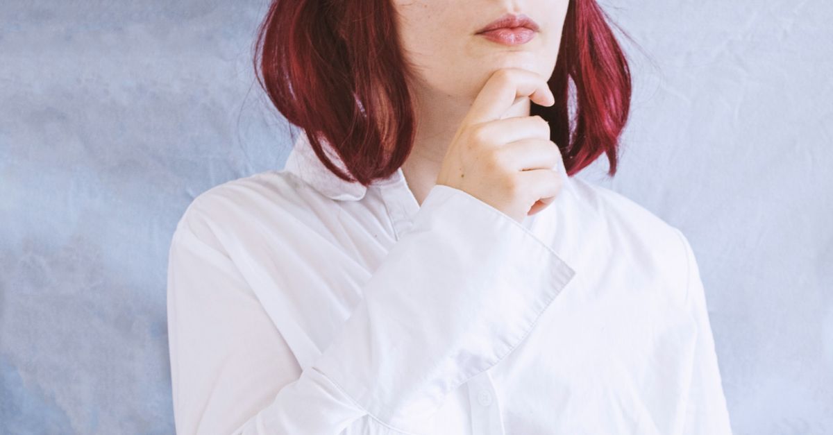 Woman in a white shirt and cloud costume deep in thought against textured backdrop.