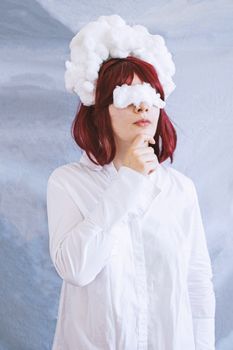 Woman in a white shirt and cloud costume deep in thought against textured backdrop.