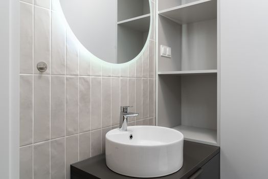 Sleek bathroom vanity with a round mirror and ceramic basin. Perfect for modern interiors.