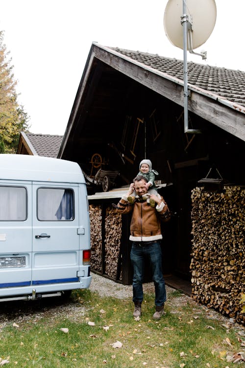 Man in Brown Jacket Standing Beside Blue Van