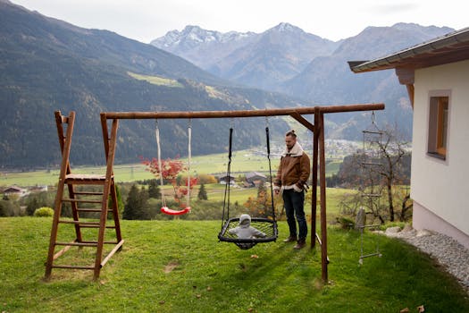 A father and toddler enjoy togetherness on a swing in a scenic mountain landscape.