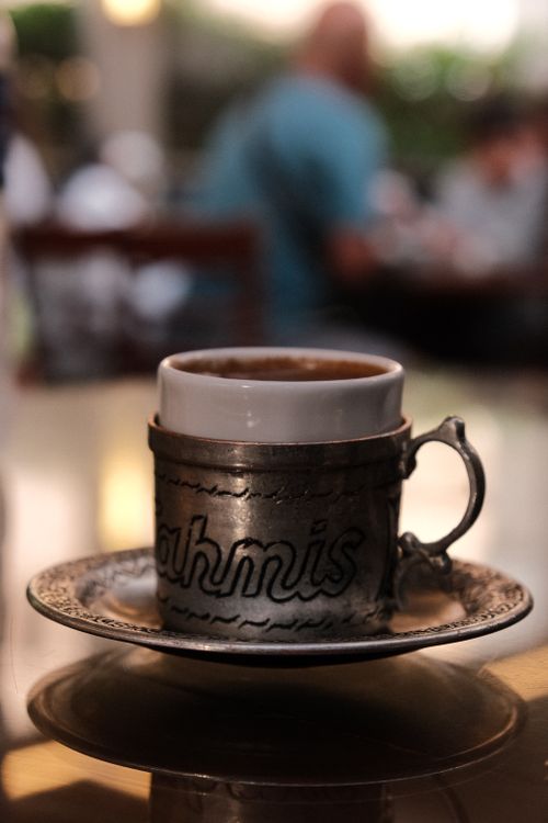 Free Intricate Turkish coffee cup with silver holder in a cozy cafe setting. Stock Photo