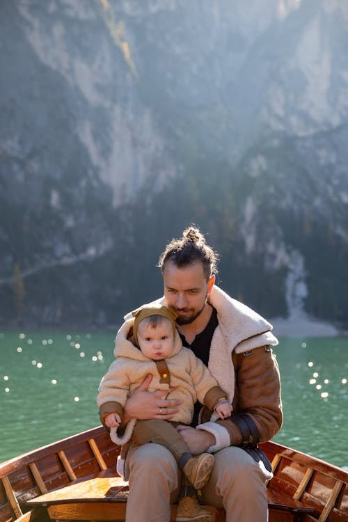 Man in Brown Jacket Hugging His Child in Brown Coat