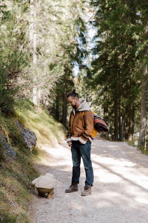 Man in Brown Jacket and Blue Denim Jeans Standing on Road