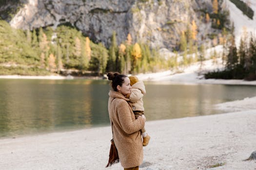 一位母亲在宁静的山湖边拥抱她的孩子，在户外展现温馨的家庭时光