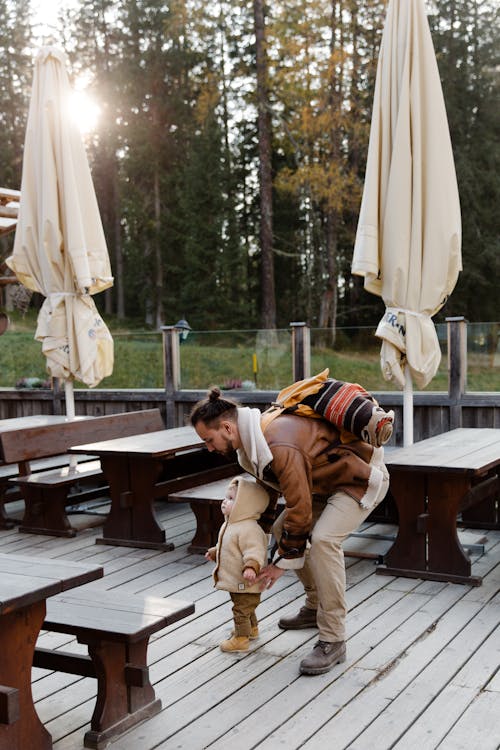 Free Man in Brown Jacket Standing Near Brown Wooden Picnic Table Stock Photo
