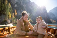 一对母亲和孩子享受宁静的乘船之旅，周围环绕着山脉和自然，反映出爱与宁静