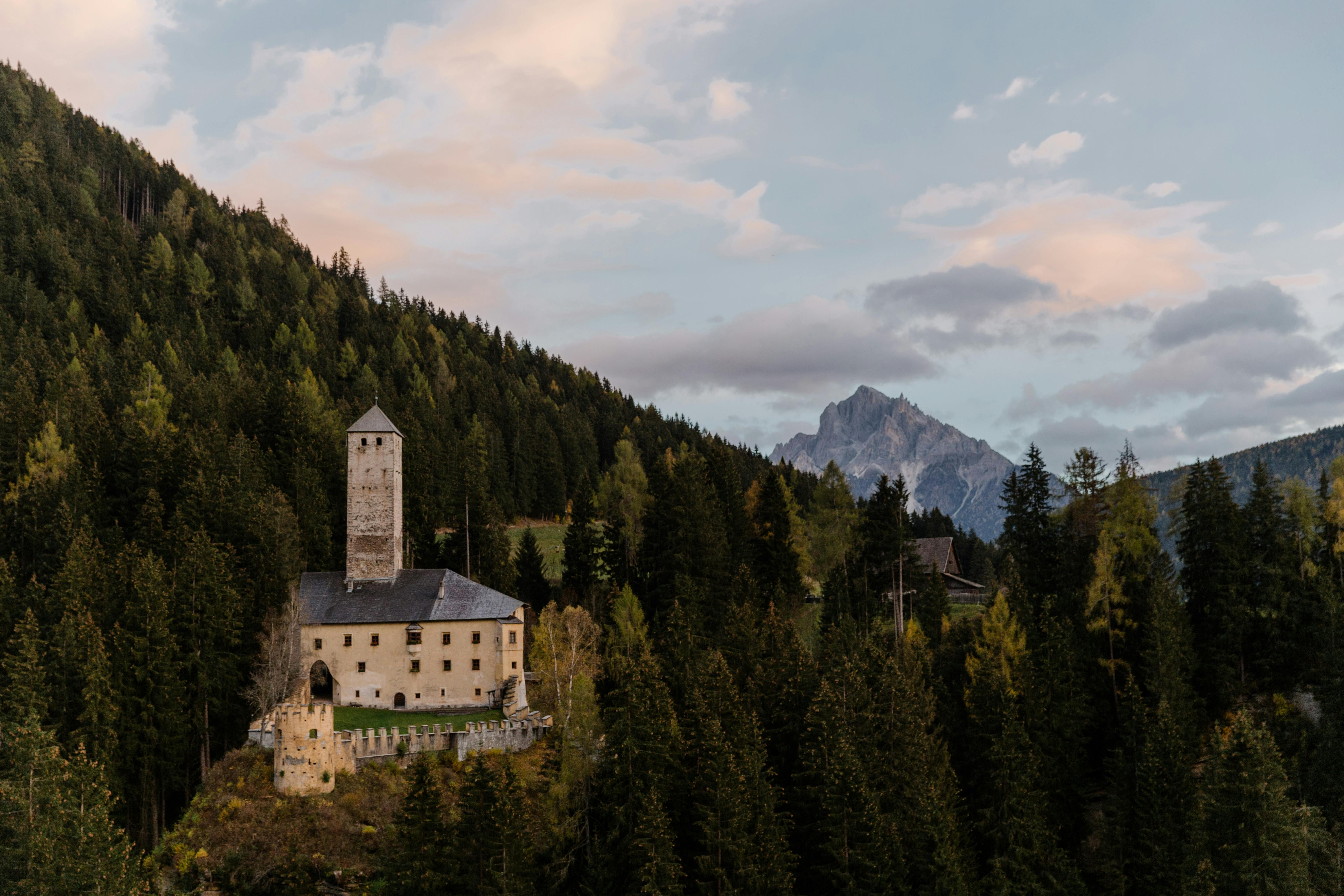 日落时分，一座令人惊叹的城堡坐落在郁郁葱葱的山区，天空显得格外壮丽