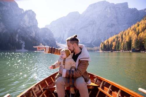 Free Man in Brown Jacket Sitting on Brown Wooden Boat Stock Photo