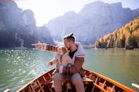 秋天，父亲抱着婴儿在船上，指着风景秀丽的山湖