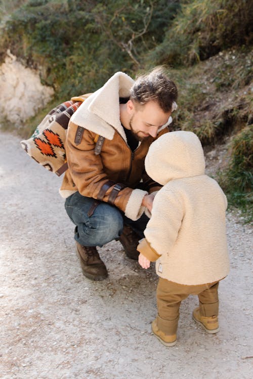 Man in Brown Jacket with His Child Wearing Brown Hoodie