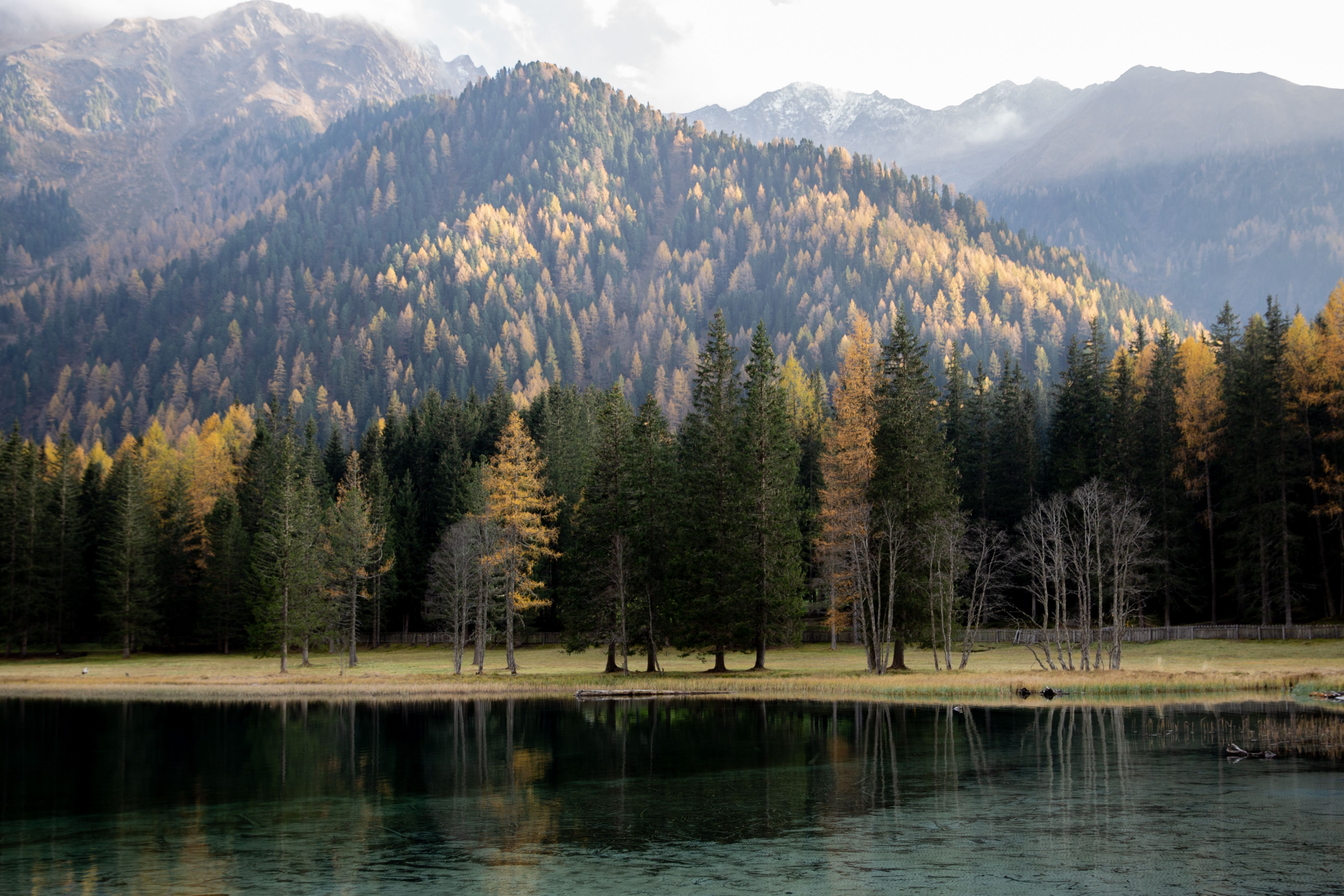 宁静的山景、平静的湖泊与充满活力的秋色倒映在水面上