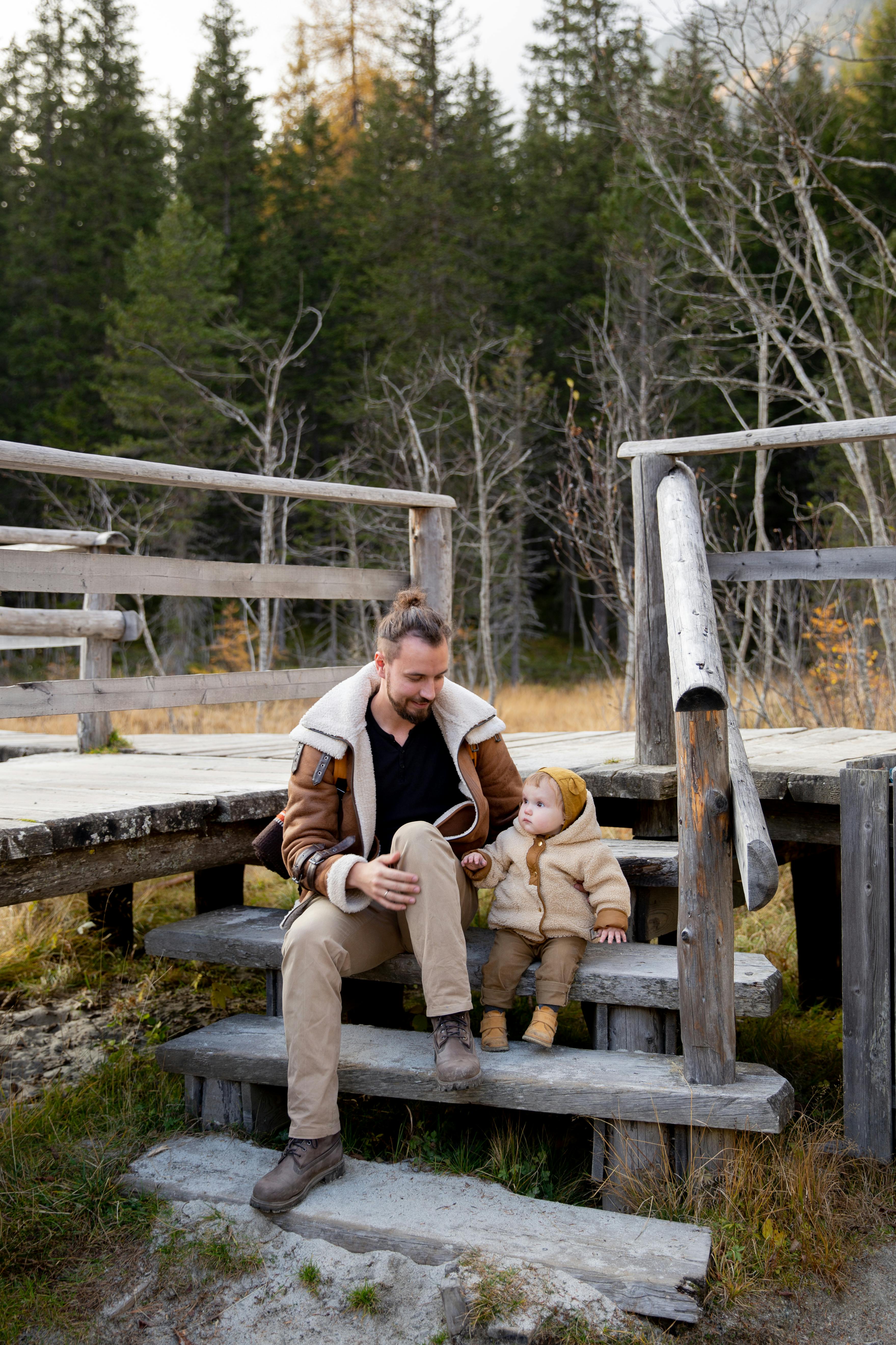 photo of man and baby sitting on wooden stairs