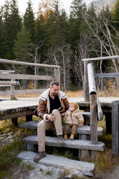 Photo Of Man And Baby Sitting on Wooden Stairs