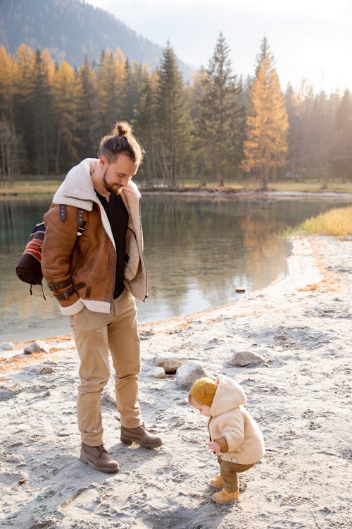 Man in Brown Jacket and Brown Pants Standing on White Sand