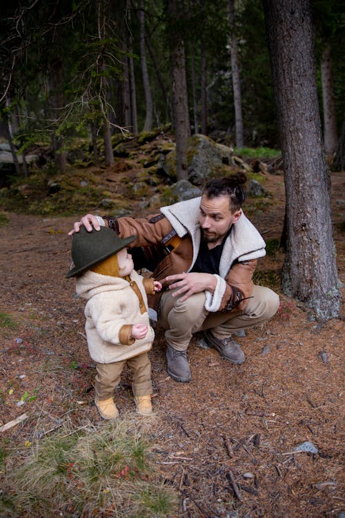 Man in Brown Jacket Putting His Hat on His Child