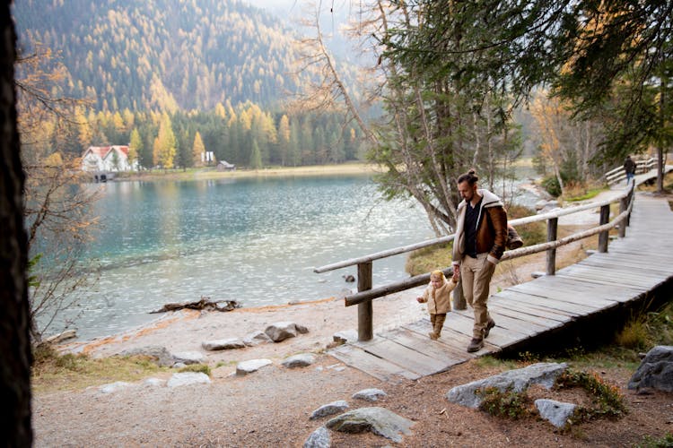 Man And Child Walking On Wooden Pathway