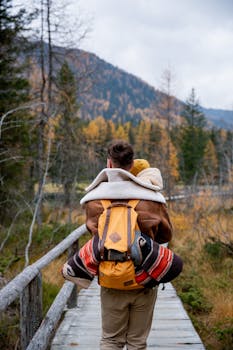 Father carrying child on a hike through a beautiful autumn forest path, embracing nature's scenic view.