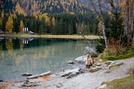 一个穿着夹克的孩子在落叶环绕的宁静湖边探索