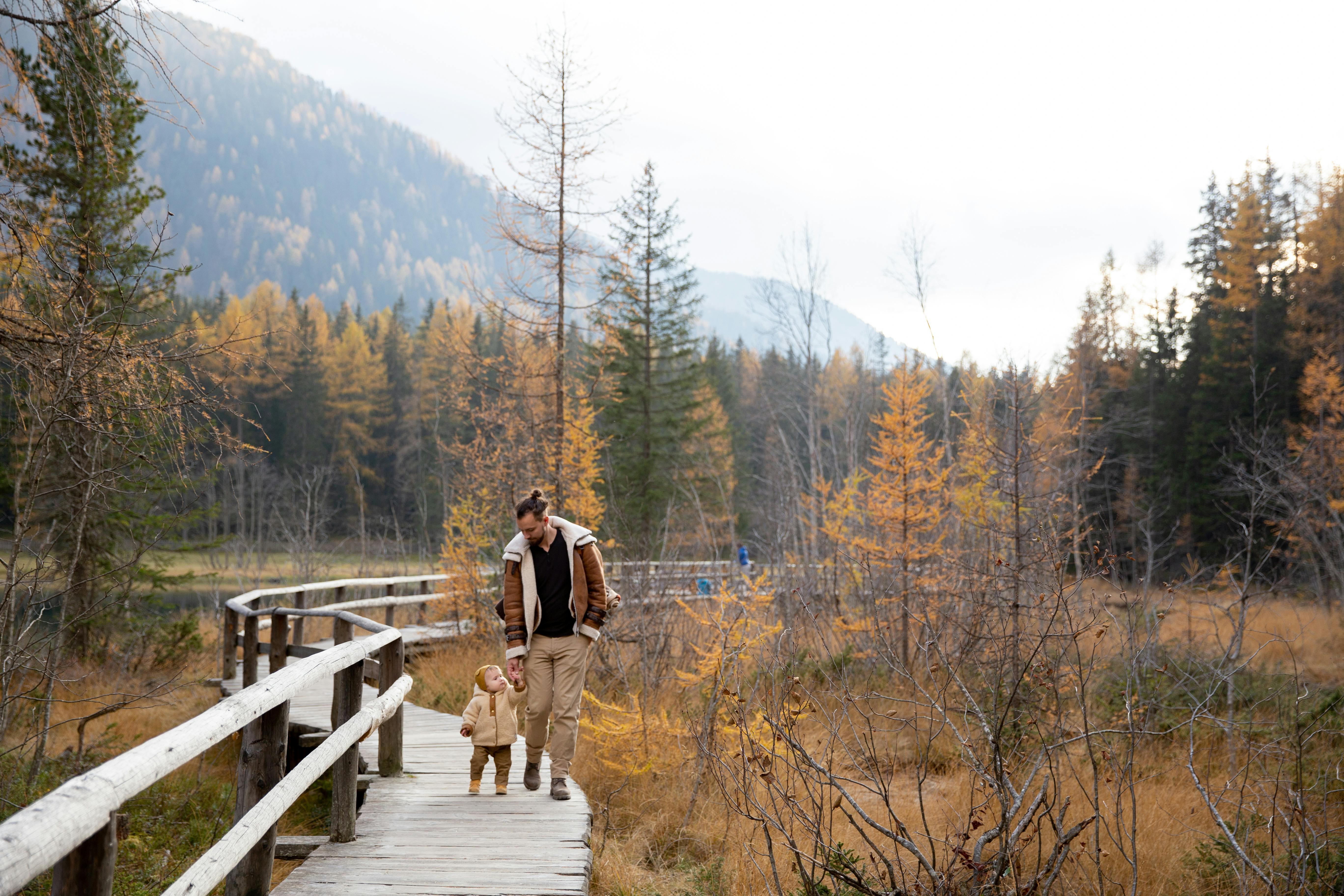 photo of man walking on wooden bridge