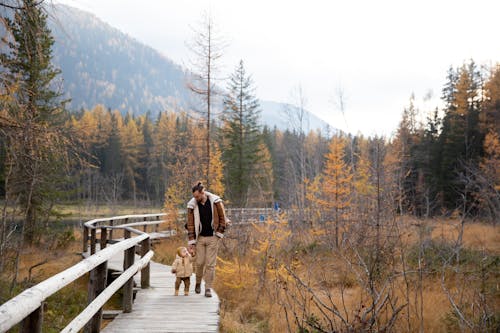 Photo Of Man Walking On Wooden Bridge