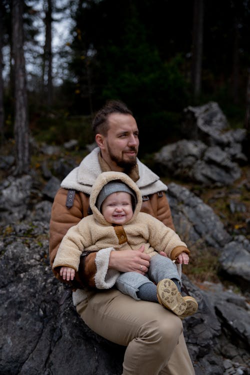 Man in Brown Coat Sitting on Rock