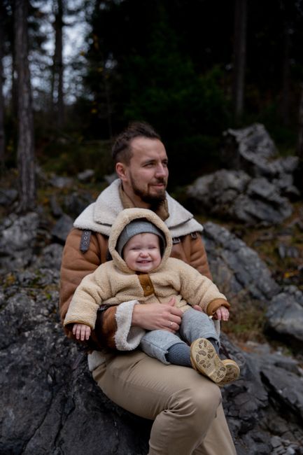 A father and child enjoying a day outdoors in a rocky forest setting during fall.
