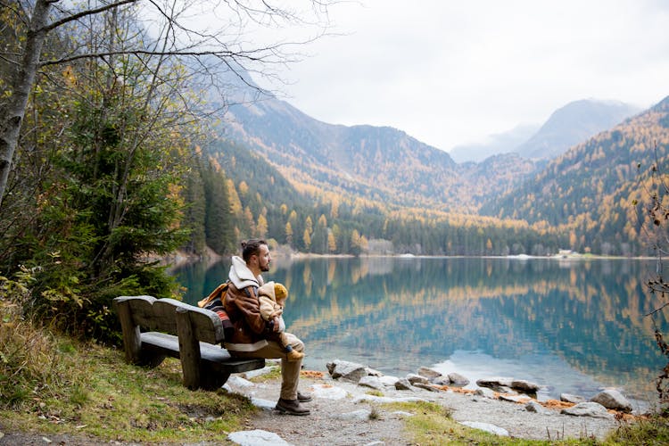 Man Sitting On Bench Near Lake