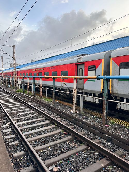 Free Red and silver train parked at a railway station in Mumbai, India with overcast skies. Stock Photo