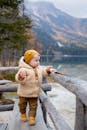秋天，一个穿着保暖外套的可爱小孩在群山环绕的湖畔地区探索