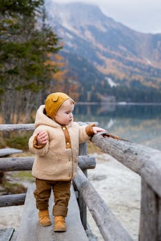秋天，一个穿着保暖外套的可爱小孩在群山环绕的湖畔地区探索