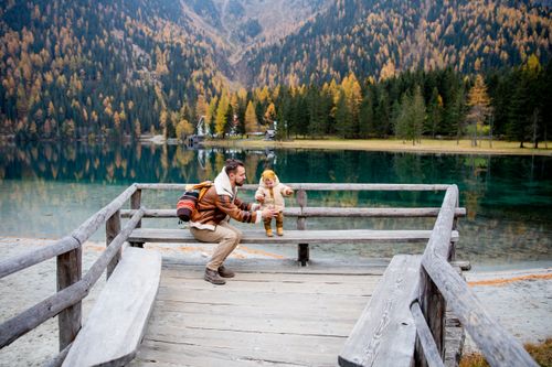 Free Father and child sharing a joyful moment by a picturesque mountain lake during fall. Stock Photo