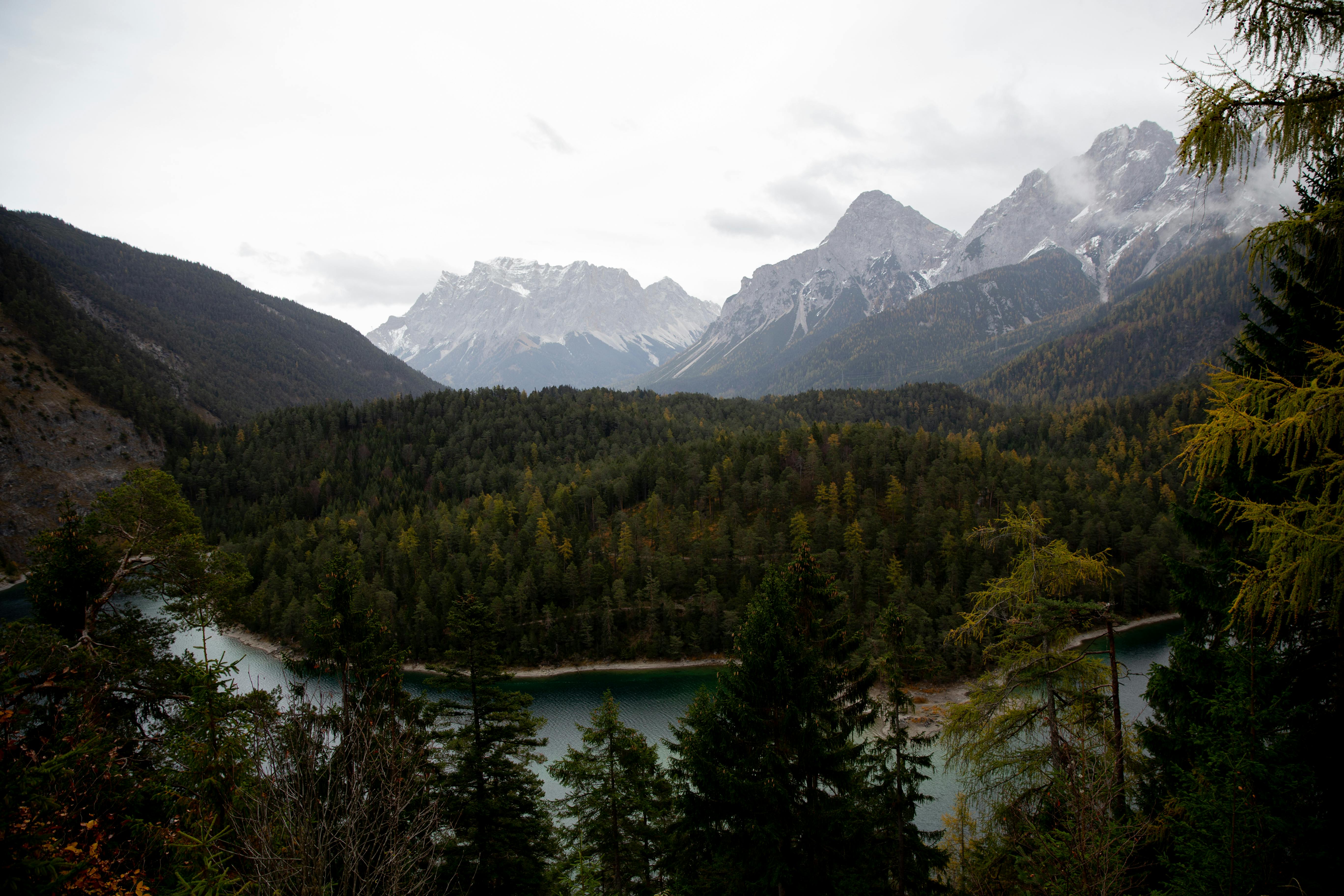 一个宁静的高山湖泊，周围环绕着茂密的森林和高耸的山峰，展现出最美的自然风光